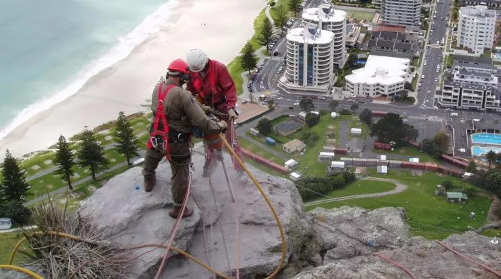 The Avalon team drilling into rock high above city buildings and beach