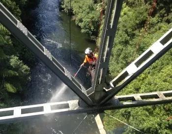 Avalon team member working on bridge structure above river