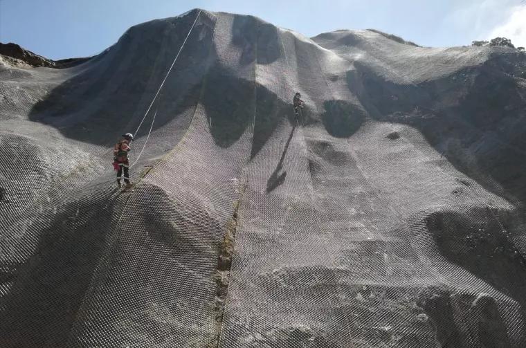 Avalon team member abseils over a fully meshed cliff