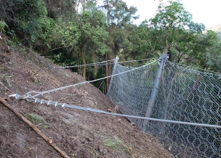Rock fall defense fencing anchored to a slope