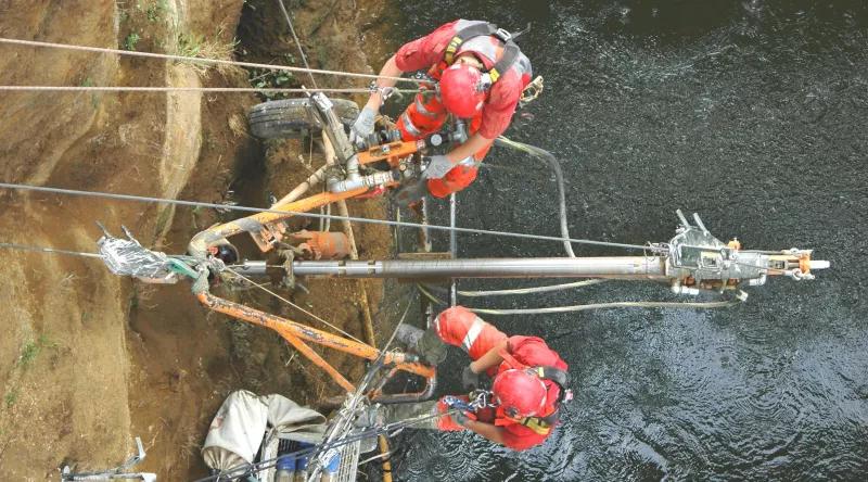 2 Avalon team members operate a rigged horizontal drill above a river